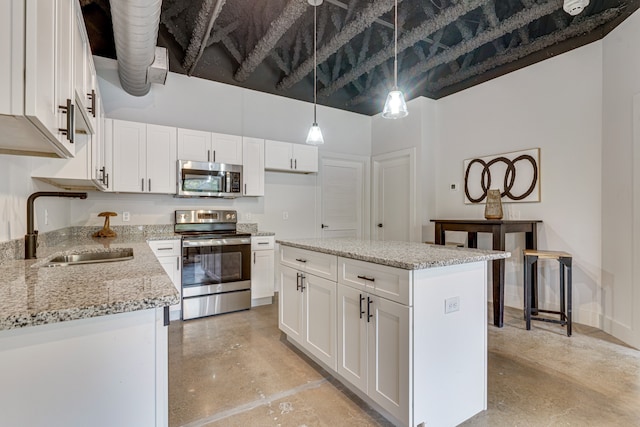 kitchen featuring appliances with stainless steel finishes, hanging light fixtures, sink, light stone countertops, and white cabinets