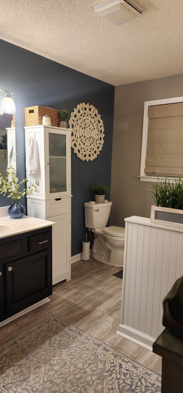 bathroom with a textured ceiling, toilet, and vanity