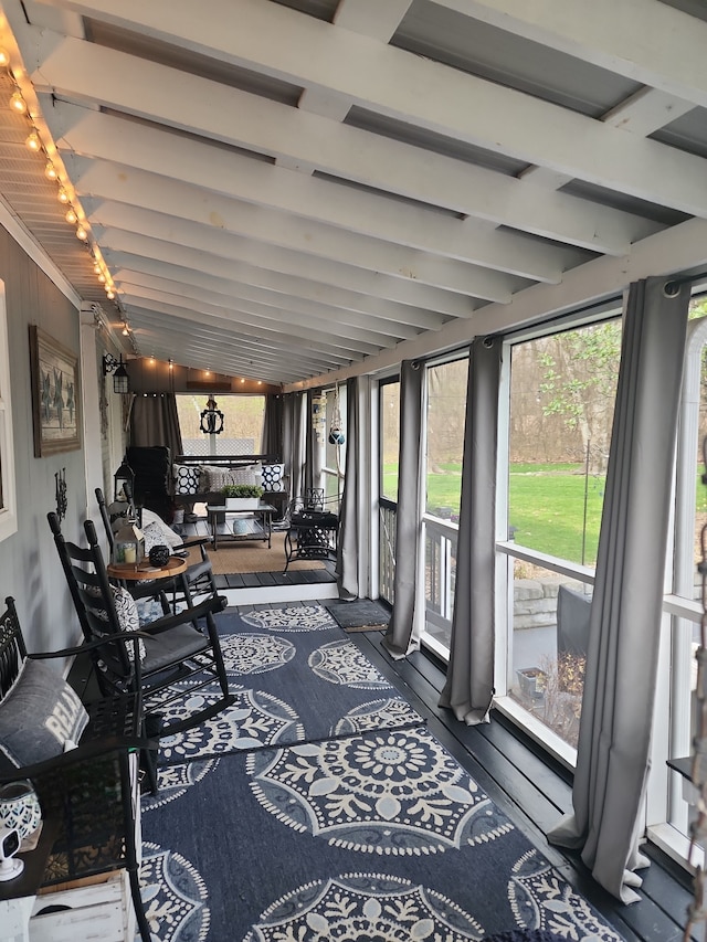 sunroom / solarium featuring beam ceiling and rail lighting