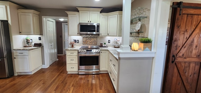 kitchen with stainless steel appliances, dark hardwood / wood-style flooring, backsplash, and light stone countertops