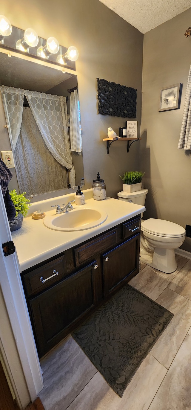 bathroom with a textured ceiling, toilet, and vanity