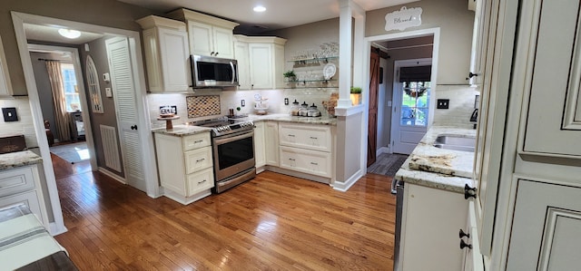 kitchen featuring stainless steel appliances, light stone countertops, and light hardwood / wood-style floors