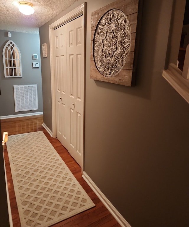 hallway featuring a textured ceiling and dark hardwood / wood-style flooring