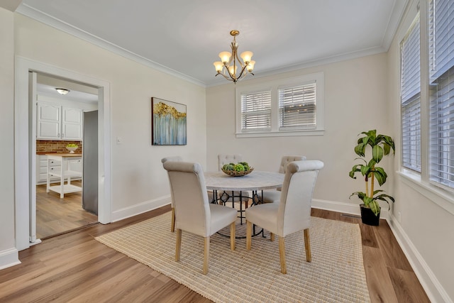 dining space with ornamental molding, light hardwood / wood-style flooring, and a chandelier