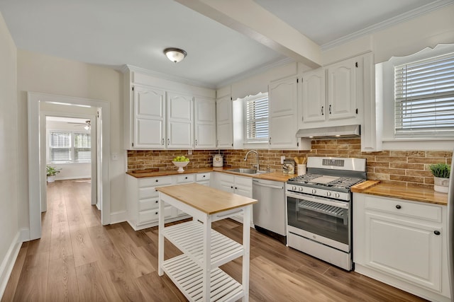 kitchen featuring sink, decorative backsplash, white cabinets, exhaust hood, and appliances with stainless steel finishes