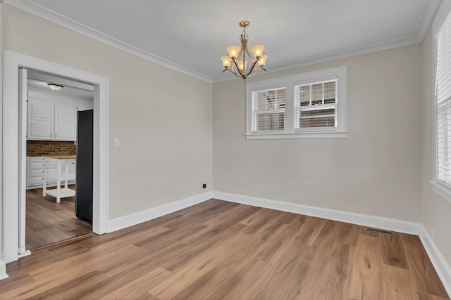 empty room with light hardwood / wood-style floors, an inviting chandelier, and ornamental molding