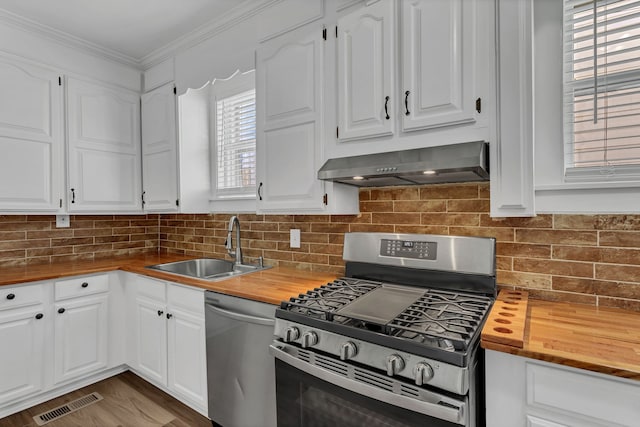 kitchen with wooden counters, ventilation hood, sink, appliances with stainless steel finishes, and white cabinetry