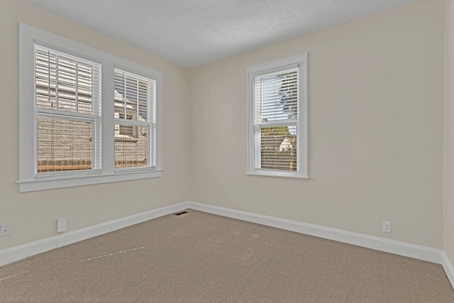 carpeted empty room with a textured ceiling