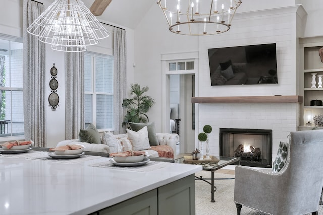 living room with a fireplace, lofted ceiling, and an inviting chandelier