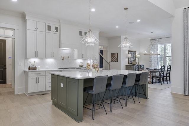 kitchen with decorative light fixtures, decorative backsplash, white cabinetry, and a large island with sink