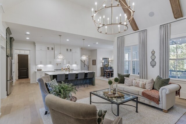 living room featuring a chandelier, beamed ceiling, and light hardwood / wood-style floors