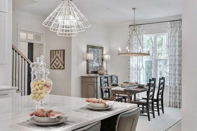 dining area featuring light wood-type flooring, ornamental molding, and a chandelier