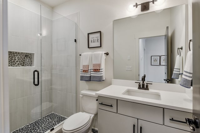 bathroom featuring vanity, a shower with shower door, and toilet