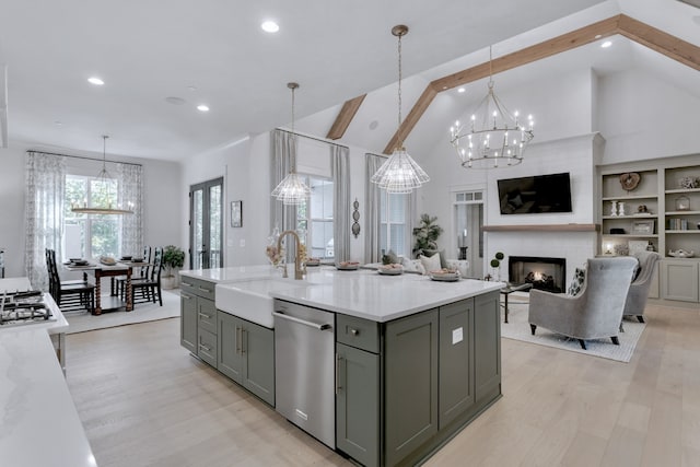 kitchen featuring stainless steel dishwasher, decorative light fixtures, a fireplace, and a kitchen island with sink