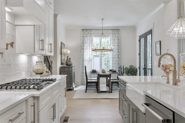 kitchen featuring white cabinets, decorative backsplash, stainless steel appliances, and an inviting chandelier