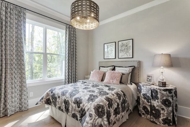 bedroom with light wood-type flooring, crown molding, and multiple windows