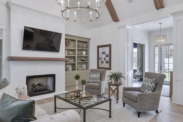 living room with ornate columns, an inviting chandelier, light hardwood / wood-style flooring, beamed ceiling, and a fireplace