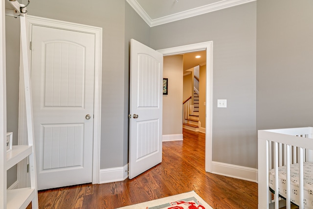 bedroom featuring dark hardwood / wood-style floors, a nursery area, and ornamental molding