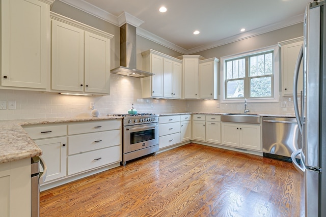 kitchen featuring backsplash, appliances with stainless steel finishes, light hardwood / wood-style flooring, and wall chimney exhaust hood