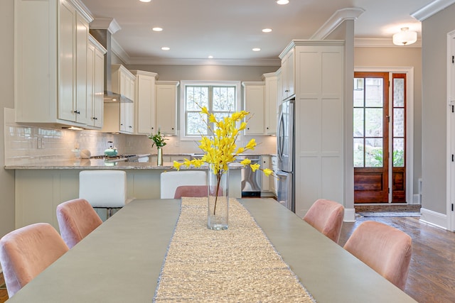 kitchen with backsplash, light stone counters, a kitchen bar, and stainless steel fridge