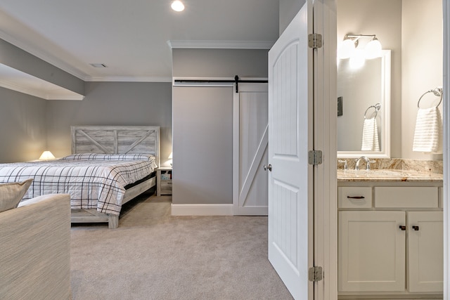 bedroom with a barn door, ornamental molding, light colored carpet, and sink