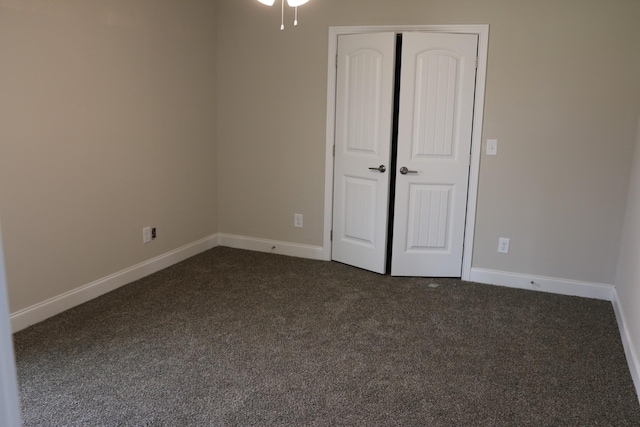 unfurnished bedroom featuring dark carpet and a closet