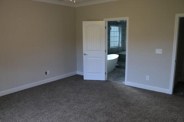 unfurnished bedroom featuring crown molding, dark carpet, and ensuite bath