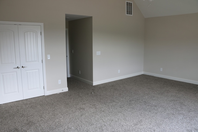 unfurnished bedroom featuring carpet, a closet, and vaulted ceiling