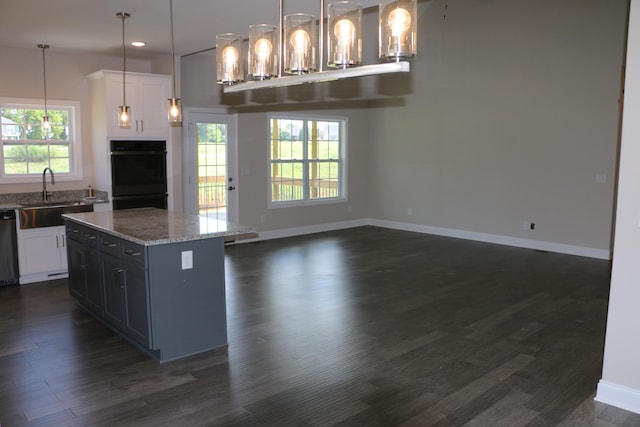 kitchen with sink, white cabinetry, black double oven, decorative light fixtures, and stainless steel dishwasher