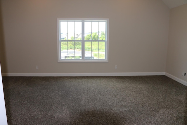 carpeted empty room featuring vaulted ceiling