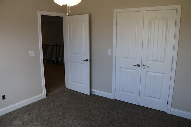 unfurnished bedroom with dark carpet and a closet