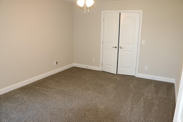 unfurnished bedroom with dark carpet and a closet