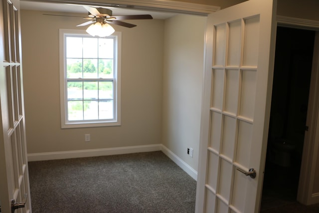 empty room featuring dark carpet and ceiling fan