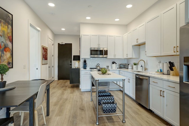 kitchen featuring backsplash, white cabinetry, light hardwood / wood-style floors, and stainless steel appliances