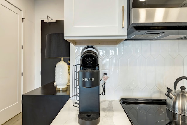 kitchen featuring backsplash, white cabinetry, and light stone counters