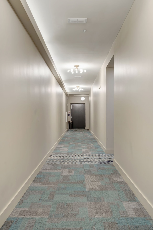 corridor featuring a notable chandelier and carpet flooring