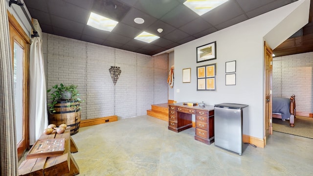 interior space featuring a paneled ceiling, brick wall, and tile flooring