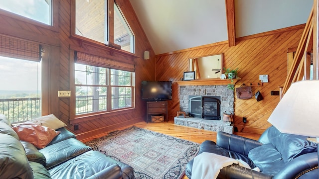 living room featuring wooden walls, beam ceiling, a fireplace, and hardwood / wood-style flooring