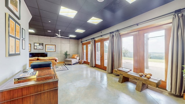 interior space with a paneled ceiling, ceiling fan, and french doors