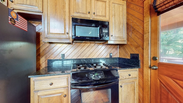 kitchen featuring dark stone counters and black appliances