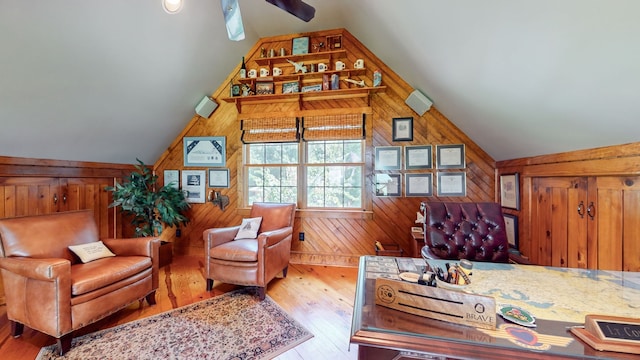 sitting room featuring wooden walls, vaulted ceiling, and wood-type flooring