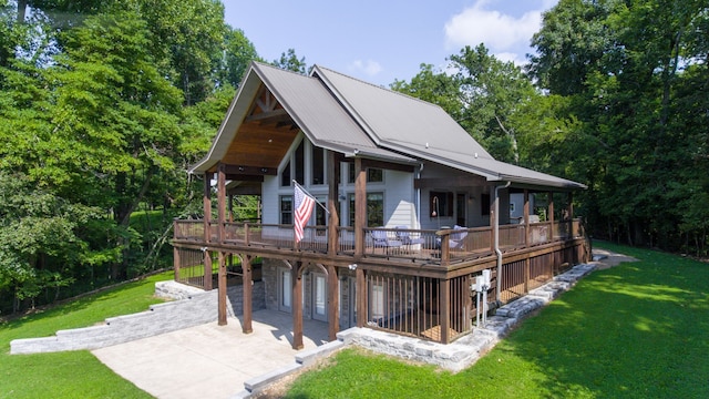 rear view of house with a wooden deck, a yard, and a patio