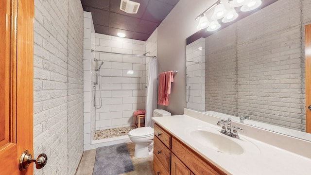 bathroom with a drop ceiling, toilet, tiled shower, vanity with extensive cabinet space, and tile floors