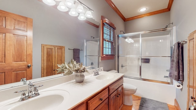 full bathroom featuring ornamental molding, combined bath / shower with glass door, toilet, and double vanity