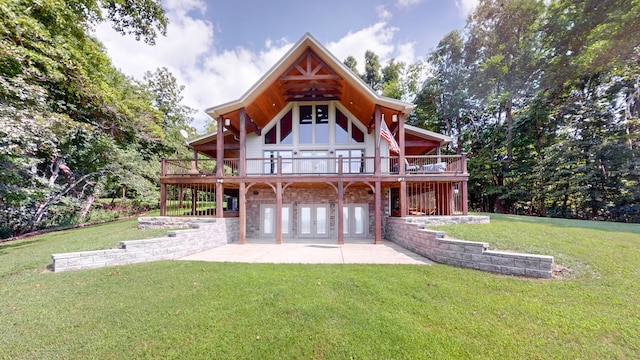 rear view of property with a wooden deck, a lawn, and a patio area