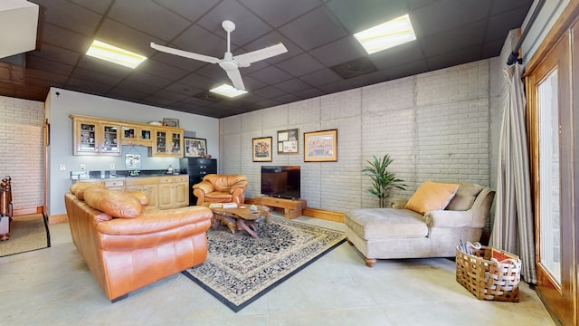 living room featuring a paneled ceiling, brick wall, and ceiling fan