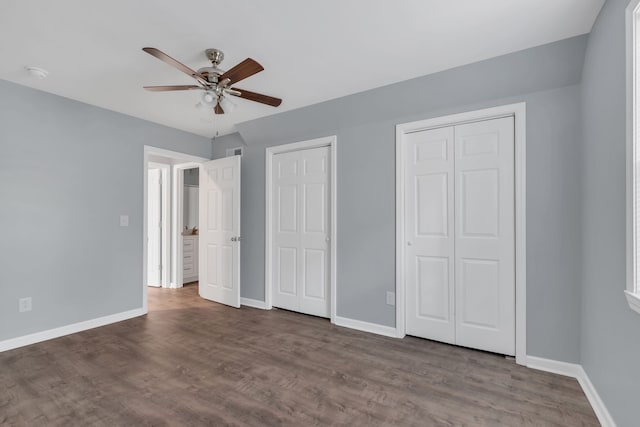 unfurnished bedroom with hardwood / wood-style floors, ceiling fan, and multiple closets