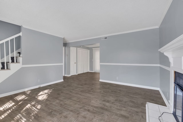 unfurnished living room with a textured ceiling, ornamental molding, a tiled fireplace, and dark hardwood / wood-style flooring