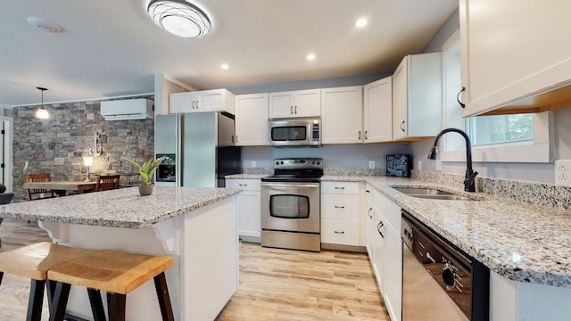 kitchen with sink, appliances with stainless steel finishes, light hardwood / wood-style flooring, light stone countertops, and decorative light fixtures