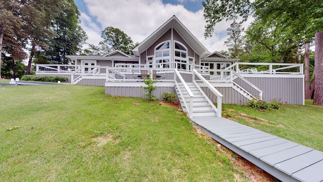 rear view of house featuring a wooden deck and a lawn